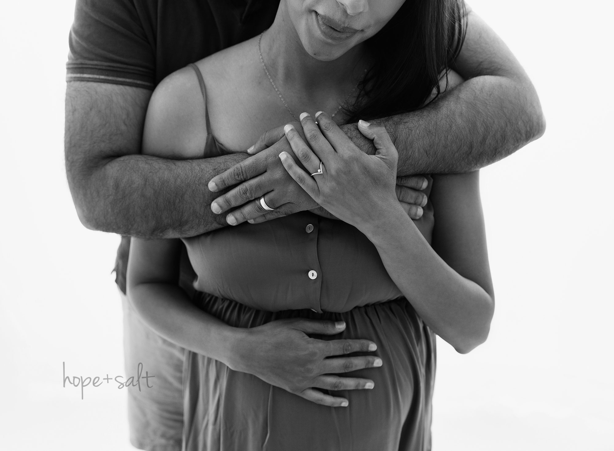 expecting-mama-N-and-husband-arms-wrapped-around-belly-oakville-studio-maternity-session-black-and-white-image